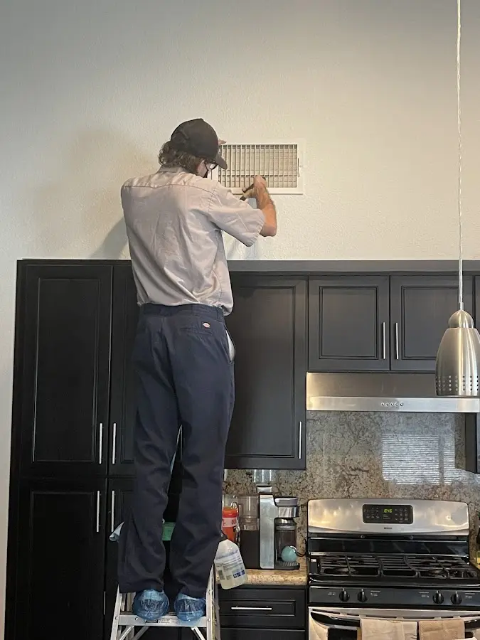 Technician inspecting an air vent during HVAC service in Millburn